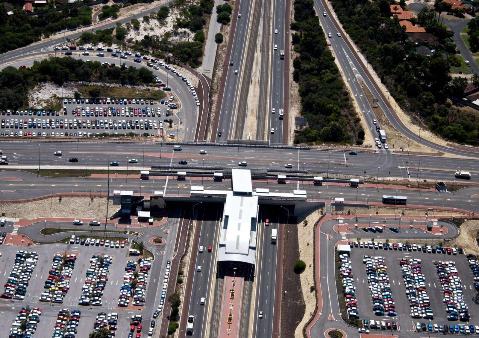 Aerial view of a rail station in a freeway median with park-and-ride car parks