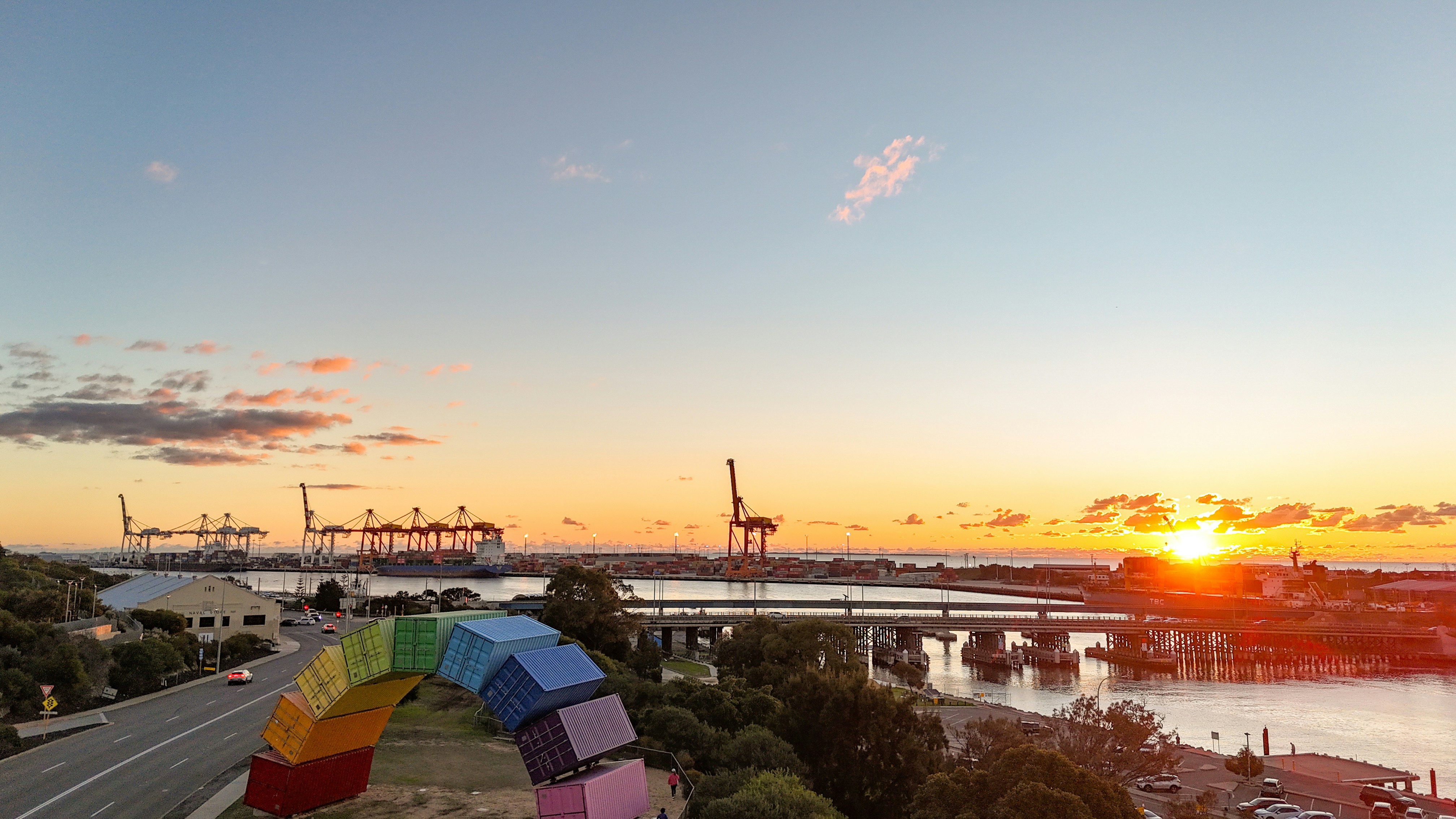 Fremantle Port at sunset — container cranes, stacked sea containers and the Rainbow sculpture